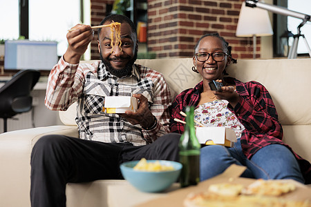 快乐的一对夫妇看电视吃面条饭图片