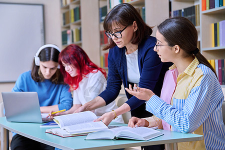 青少年学生群体和在图书馆书桌上的师范学习导师女性桌子考试课堂小学生团体学校中学教育图片