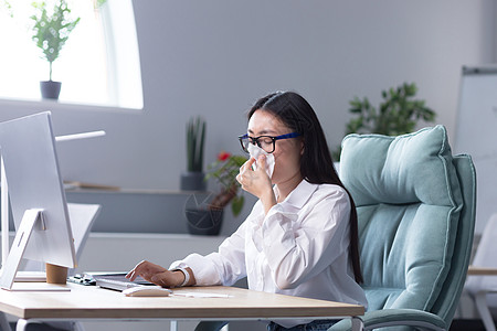 一位年轻的亚洲女商务人士病倒 用餐巾纸擦他的鼻子 (Y 我)图片