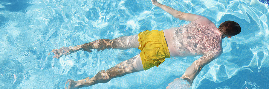 穿泳裤的男性在水上漂浮在肚子的水上 游泳池中的清水图片