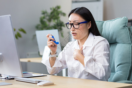 一位年轻的亚裔女性坐在办公室里 感到很不爽 (她)在办公室里图片