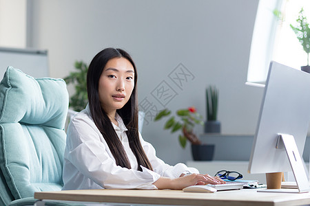 特写照片 坐在电脑桌前的一位年轻亚裔女秘书的画像图片