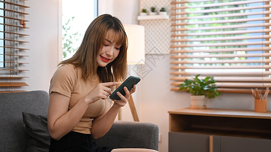 年轻美女使用手机与朋友聊天 同时在家舒适沙发上安睡时用手机聊天;以及图片