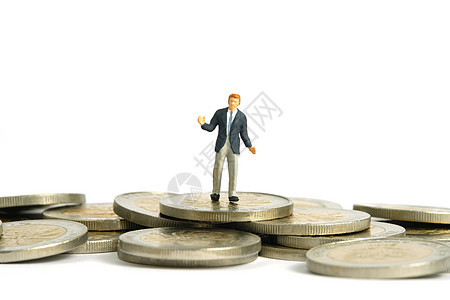 迷你人物玩具雕像摄影 金融计划概念 一个摇摆着的商务人士站在硬币堆积之上 在白背景上孤立无援图片