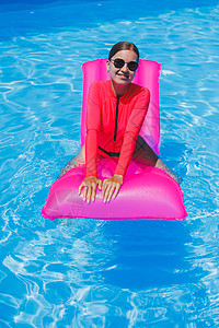 身着太阳镜和粉红色比基尼的快乐年轻女子 漂浮在游泳池边可充气床垫上游泳衣女孩魅力日光浴天线泳装游泳闲暇金发女郎假期图片