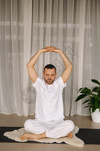 穿白色运动服的男子正在健身房做瑜伽 健康生活方式的概念是衣服收费身体地毯运动活力姿势活动成人塑料图片