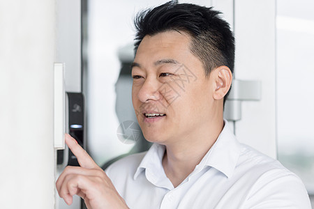 一个年轻的亚洲男子的肖像 打电话到家里的对讲机 按下按钮衬衫入口相机租户手指技术键盘客人安全房子图片