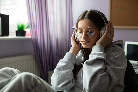 一名少女闭着眼睛在无线耳机上听音乐 而且闭着眼睛窗户娱乐测试戴眼镜个人现代性扇子眼镜时间女子图片