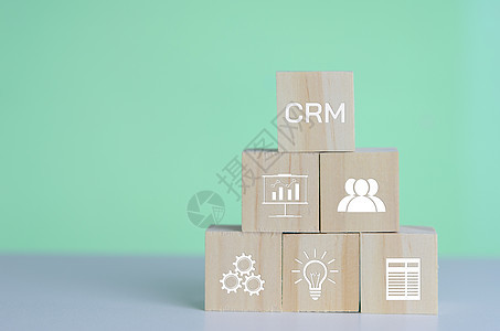 背景和复制空间上带有 CRM 客户关系管理自动化系统软件符号的木制立方体 业务概念图片