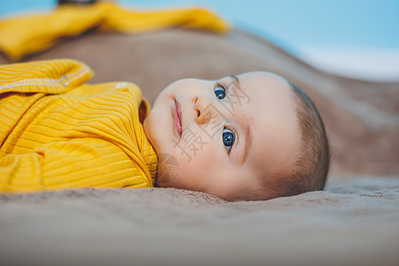 一个四个月快乐的婴儿 躺在一个毛毯上 婴儿肖像 孩子抱着他的头女孩蓝色寝具卧室毯子格子房间新生身体苗圃图片
