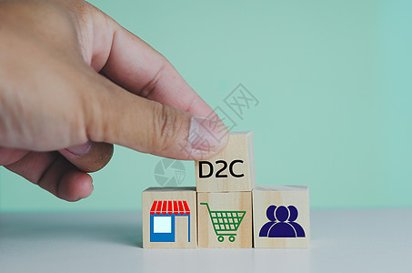 手把直接对消费者D2C的木制立方体放在桌子上 复制空间营销白色字母网站社会职业商业战略金融工作图片