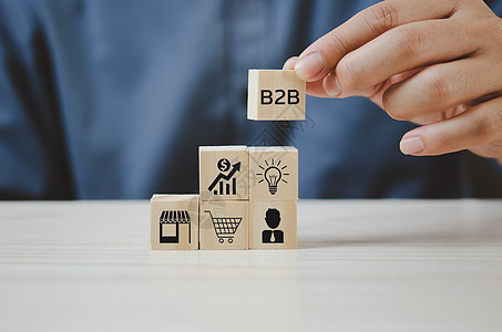 手工将带有 B2B 企业对企业图标和符号的木制立方体放在桌子上并复制空间 商业概念图片