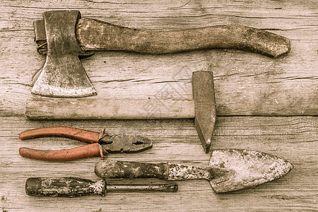 旧木板表面的旧染色斧头 锤子 钳子 铁和螺丝刀图片