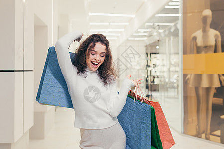快乐和满意的年轻女人 女孩在购物中心购物 展示他们购买的东西 彩色纸袋 欢欣鼓舞 大笑开支购物者裙子销售头发零售成人购物狂微笑精图片