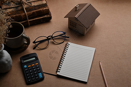 木桌上的小房子模型 计算器和眼镜 抵押贷款和房地产投资概念图片