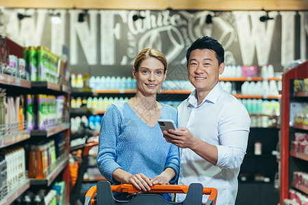 超级超市夫妇的家族肖像 在购物时微笑和看相片图片