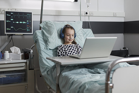 正在看笔记本电脑漫画的接受治疗的年轻病人图片