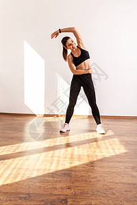 苗条的女性举手弯曲到一边 做伸展肌肉锻炼 柔韧性练习图片
