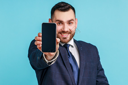 在线服务 技术 满意的快乐男人穿着官方风格的西装 站着拿出手机 对着镜头大笑图片