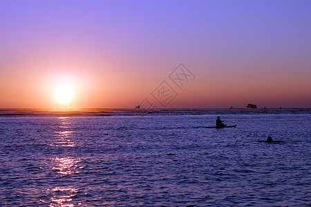 日落时人们和船只在海洋上沉入水中图片