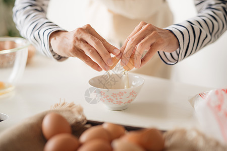 身穿米花围裙的严肃男性将鸡蛋冲进金属碗的横向镜头牛奶厨师白色甜点面粉蛋黄面包蛋糕女士女性图片