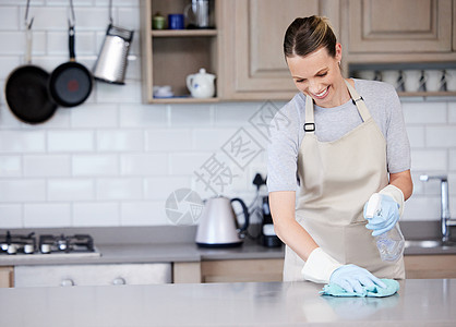 一位年轻女子用洗涤剂和衣服擦厨房的地表 在家中铺上清洁剂和布图片