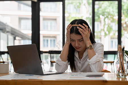 年轻迷人的亚洲女商务人士在办公桌前睡觉 打瞌睡或小睡 疲惫的女商务人士在办公室拿着账单和文件夹 疲惫的年轻女商务人士带着笔记本电图片