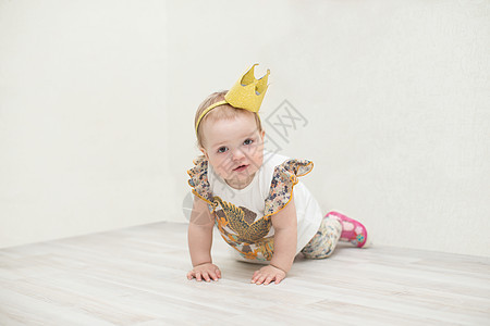 一岁女孩戴着皇冠 小公主爬在地上 跳到地板上幸福孩子婴儿蠕变衣服膝盖快乐姿势童年女性图片