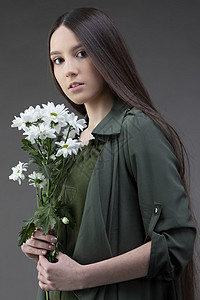一个美丽的年轻女孩 天生丽质 留着光滑的长发 手捧一束白菊花背景工作室白色花束化妆品深色花朵女士黑暗皮肤图片