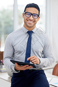 年轻的混血商务人士拿着和使用数字平板电脑站在办公室工作 一位心满意足的西班牙裔男性商务人士在工作时在数字平板电脑上打字图片