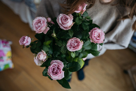 一位年轻女子高视 她拿着花盆和粉红玫瑰灌木玫瑰庆典气氛礼物问候语女士花束女性花店场合图片
