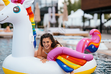女人在泳池里用可充气的独角兽玩具床垫漂浮火烈鸟海滩粉色水池日光浴天堂泳装女士比基尼旅行图片
