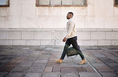 独自旅行的黑人商务人士 一个非洲裔美国商务人士带着行李在城里走来走去 同时在城市里看起来很时尚图片
