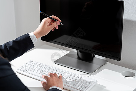 女商务人士在桌上的膝上型键盘上键入最新更新 并用笔指出重要想法 办公室里的女人在电脑上写迟来的信息团队技术桌子地点商务经理电脑显图片