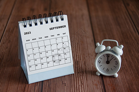 9月2023日 白桌日历 闹钟指向12点 在木制桌子上图片