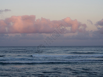 美丽的粉色和紫色黎明 在海面上 海浪向海岸滚动图片