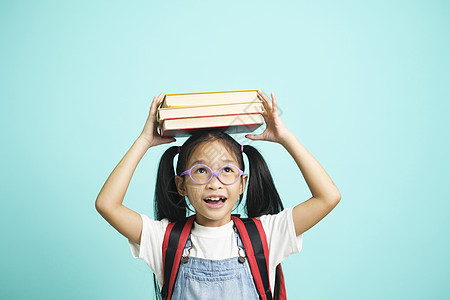孩子们去上学 女孩滑稽地笑着 孩子们戴着眼镜的女孩把书放在头上家庭作业喜悦微笑老师活动瞳孔学生电脑教育女儿图片