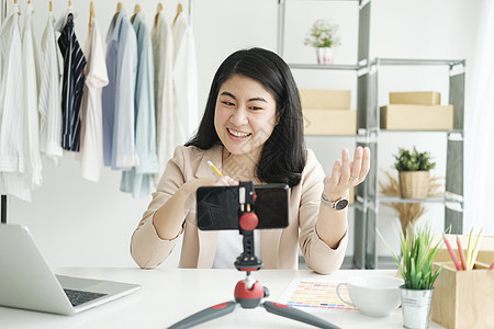 商业女商务人士在提供重要建议的同时 还播放妇女服装的视频流传产品衬衫仓库购物店铺包装营销检查网上购物互联网图片