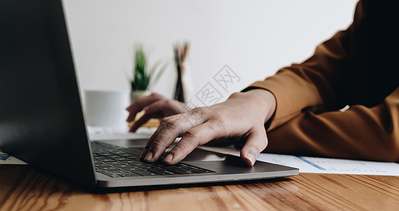 在线分析坐在桌上与笔记本电脑连接的女士正在工作 在键盘上打字 手关紧背景
