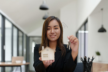 一名亚洲银行女雇员在签署文书工作合同后 将房子和钥匙交给了客户 她被描绘成一幅肖像财产公寓签名文档土地办公室商业经纪人保险计算器图片