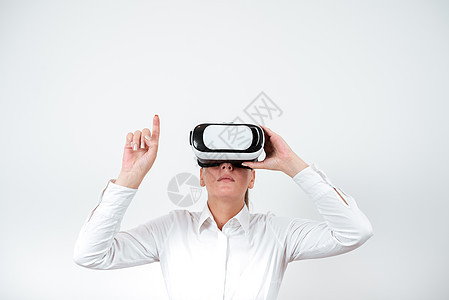 女人戴着 Vr 眼镜 用一根手指指着重要信息 有虚拟现实眼镜和显示重要信息的女商务人士想像力耳机乐趣商务人士电子游戏衬衫创新成人图片