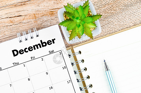 2022年12月的案头日历和用木制背景笔画的开放日记图片