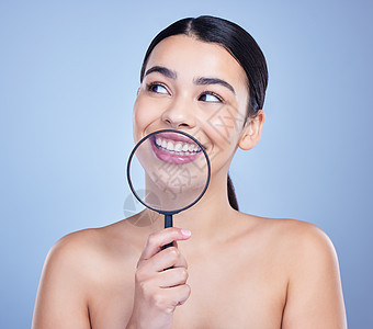 一个美丽的混合种族女子 冒着放大镜的姿势 年轻的西班牙人痴迷于口腔卫生 面对灰色复本背景图片