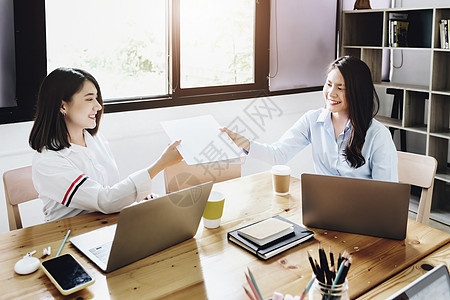 两名公司女雇员在互交文件夹时 愉快地对对方笑了起来顾客预算项目合同规划师市场桌子成功审计秘密图片