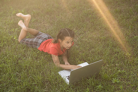 小女孩在夏花花园用笔记本电脑学习说谎教育屏幕家庭作业触控板电子产品童年技术互联网图片