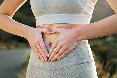 锻炼应该被视为对心灵的礼赞 一个健康的年轻女人在她的肚子上形成一个心形图片