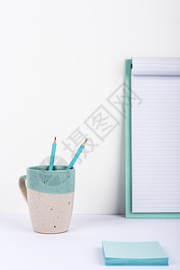 有里面两支铅笔的杯子在有重要消息和笔记的剪贴板的办公桌上安置了 有笔的杯子在桌上有备忘录的重要公告提出图片