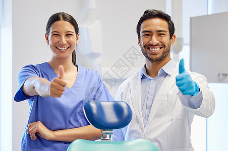 两个年轻的牙医在诊疗室露出拇指的肖像 看上去很像一个大个子图片