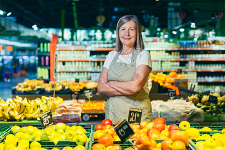 一名超市工人的高级灰发妇女肖像画 劳动者传播水果客户老年杂货店市场消费者老板蔬菜围裙女性相机图片