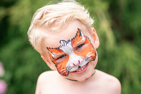 可爱的小男孩 用他的脸上涂漆活动蓝色老虎微笑化妆品幼儿园艺术生日面具乐趣图片